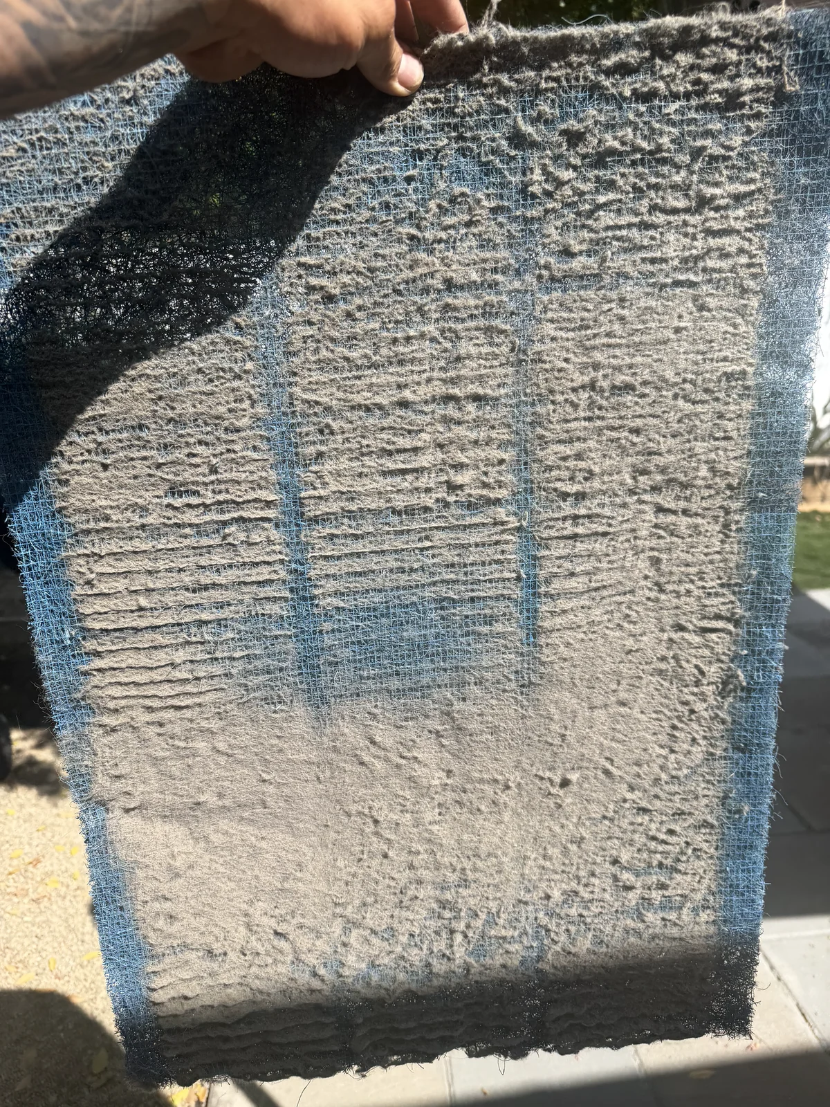 A blue AC filter covered with dust before cleaning.