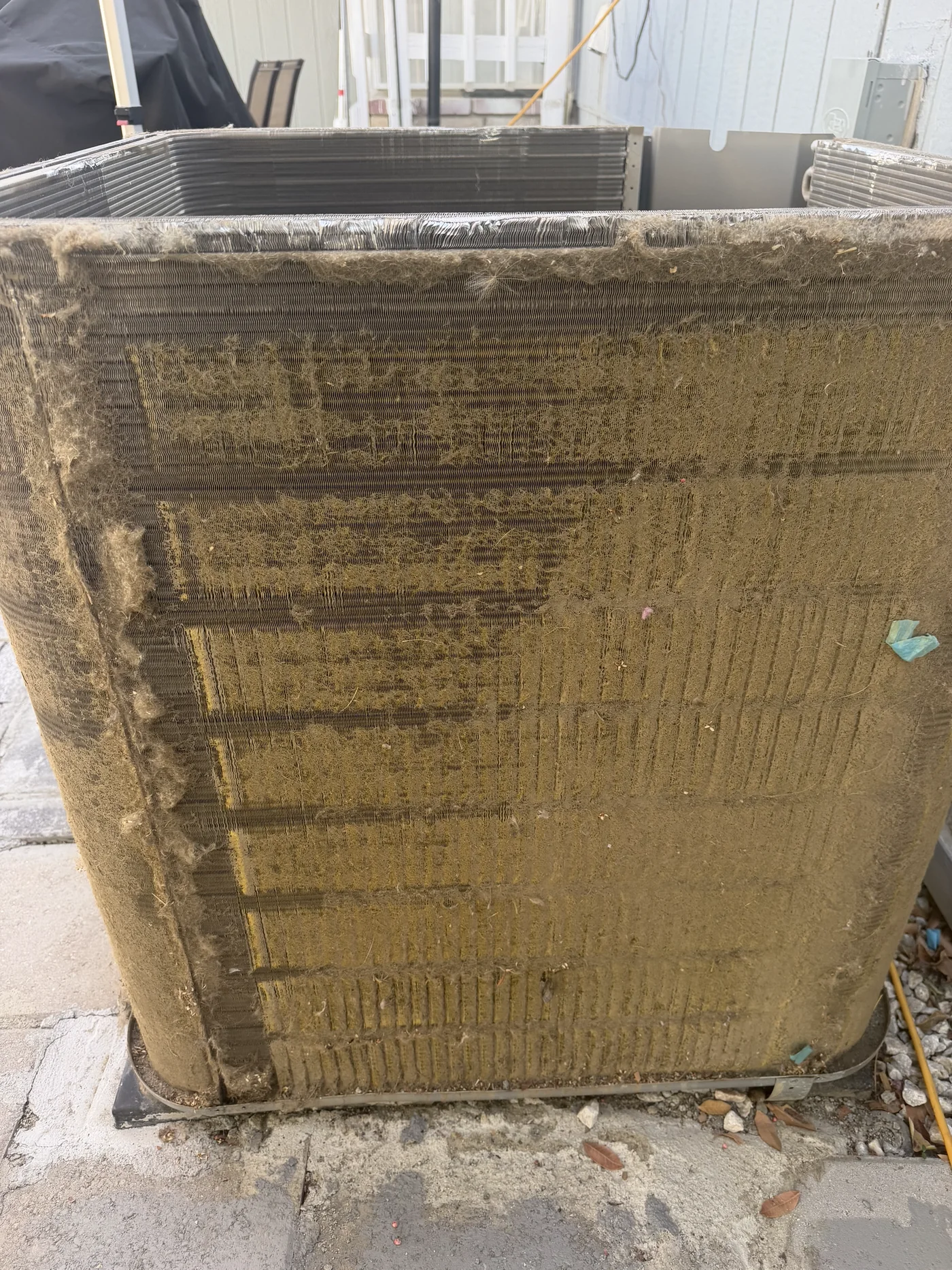 Outdoor condenser coil with dirt buildup before maintenance cleaning.