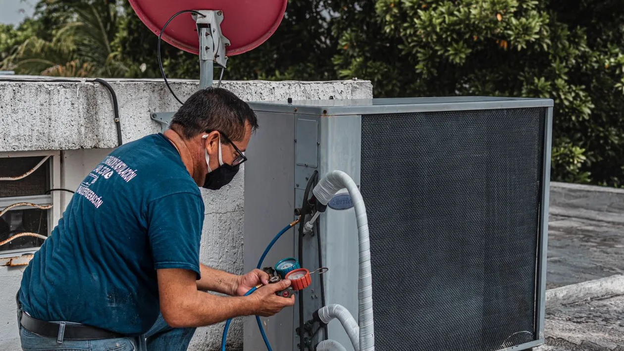 Technician checking an outdoor air conditioner with service gauges