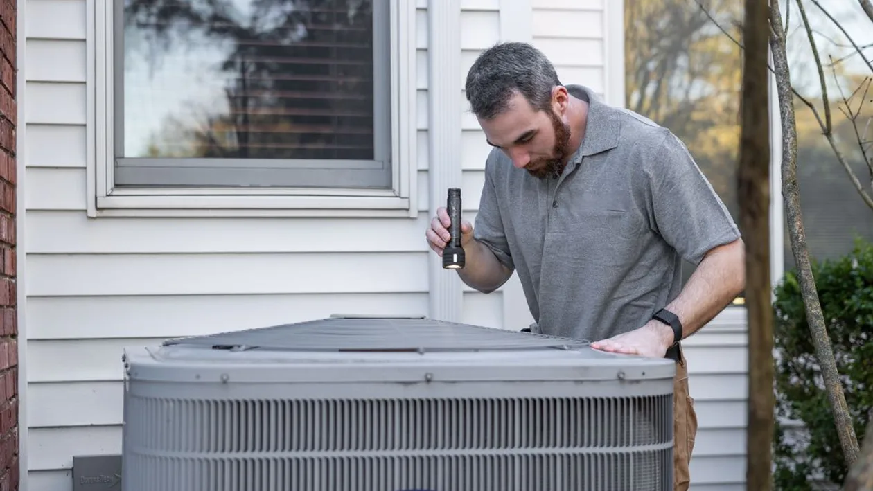 HVAC technician inspecting an outdoor heating and cooling unit